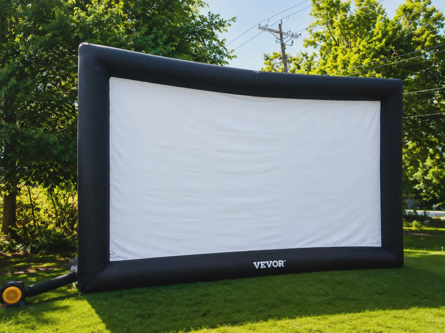 Large inflatable outdoor movie screen with a black frame and white projection surface set up on grass